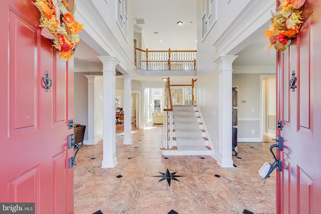 foyer entrance with a high ceiling, ornate columns, and crown molding