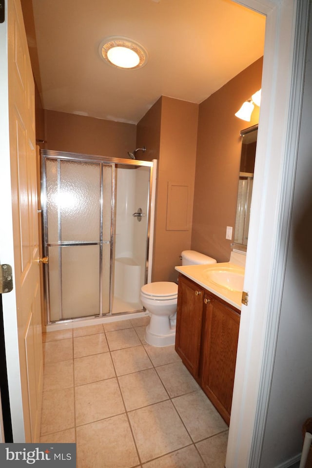 bathroom featuring tile patterned flooring, vanity, toilet, and a shower with shower door