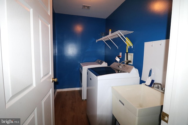 washroom featuring washing machine and dryer, sink, and hardwood / wood-style flooring