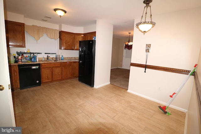 kitchen with pendant lighting, black appliances, sink, and light stone countertops