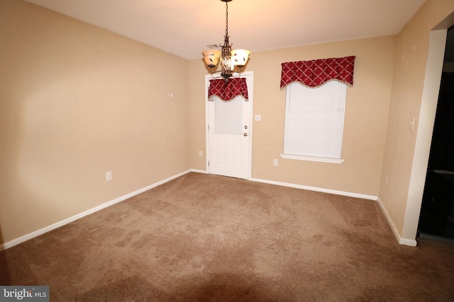 carpeted spare room with a notable chandelier