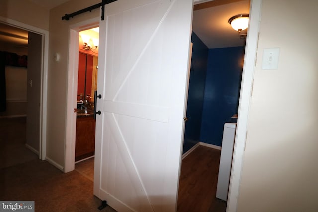 hall featuring a barn door and dark wood-type flooring