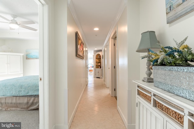 hallway with ornamental molding and light tile patterned floors