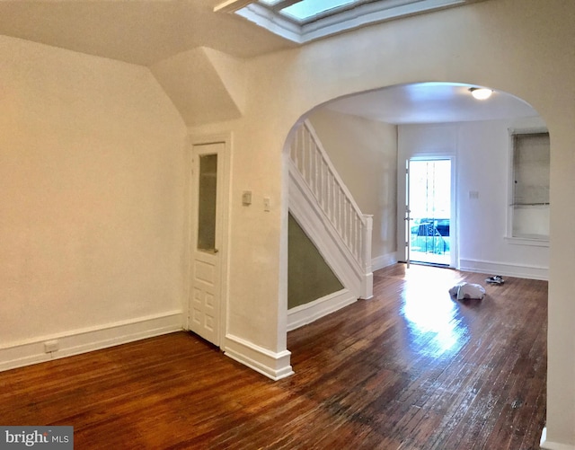 foyer with dark wood-type flooring and lofted ceiling with skylight