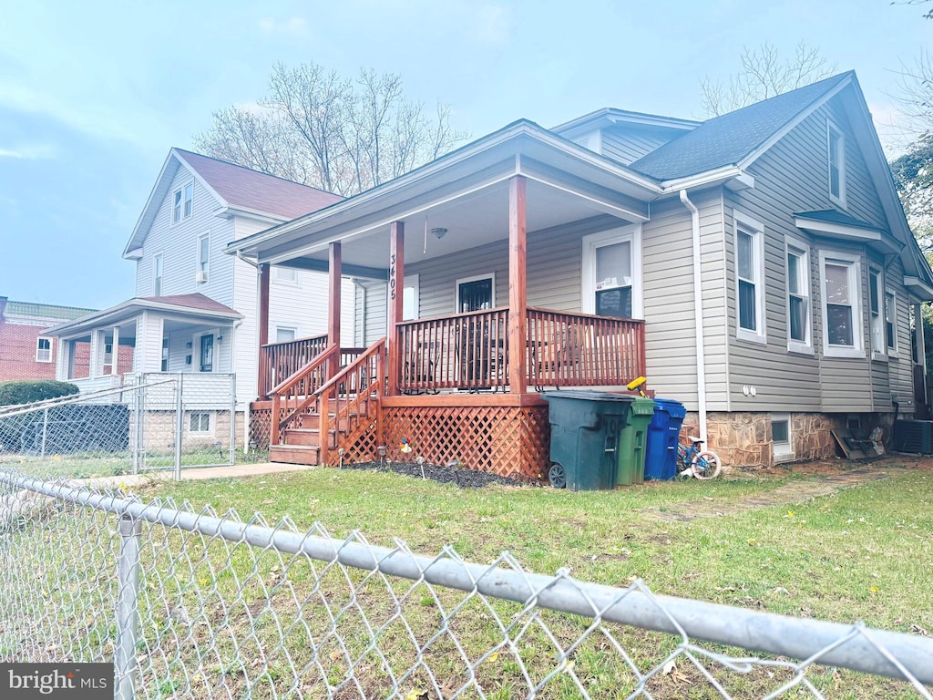 view of front of home featuring cooling unit, covered porch, and a front lawn