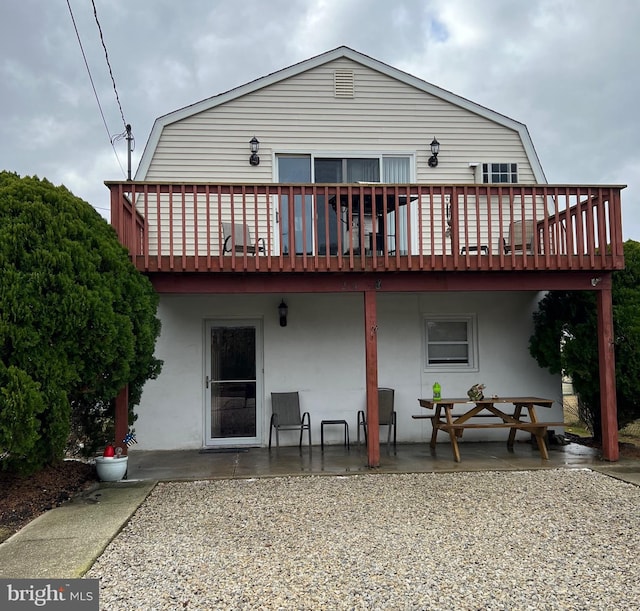 rear view of property featuring a wooden deck and a patio area