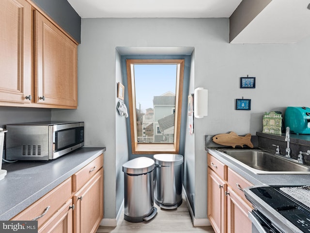 kitchen with light brown cabinetry, electric range, light hardwood / wood-style flooring, and sink