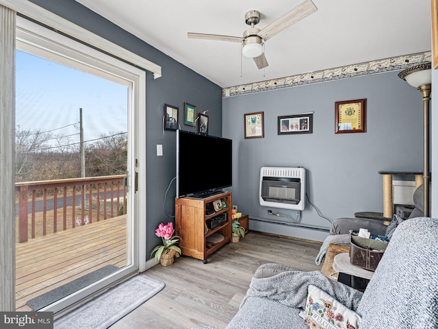 living room featuring heating unit, ceiling fan, light wood-type flooring, and a baseboard heating unit