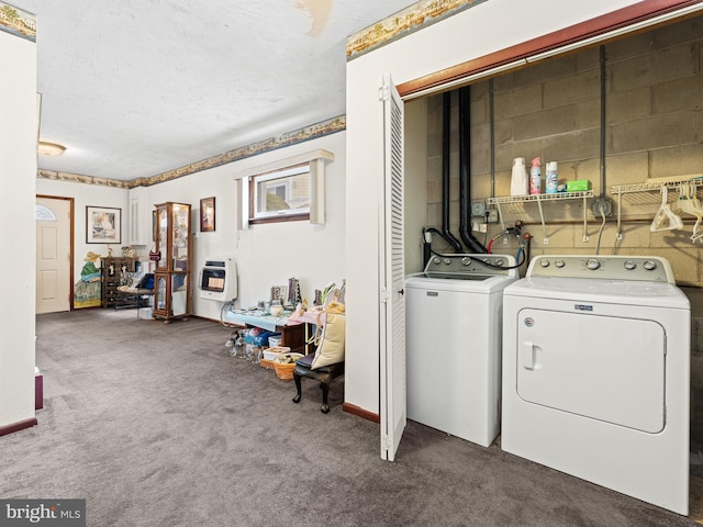 clothes washing area with a textured ceiling, carpet floors, heating unit, and washer and clothes dryer