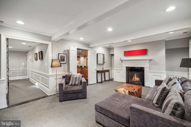 carpeted living room featuring beam ceiling and ornamental molding