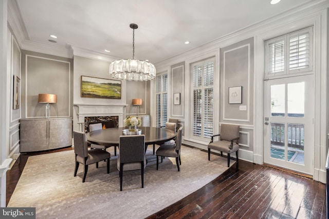 dining space featuring dark hardwood / wood-style floors, crown molding, a fireplace, and a chandelier