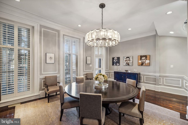 dining area with crown molding, hardwood / wood-style floors, and an inviting chandelier