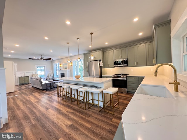 kitchen featuring sink, appliances with stainless steel finishes, a kitchen breakfast bar, dark hardwood / wood-style floors, and hanging light fixtures