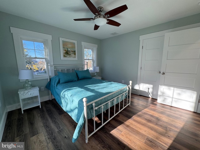 bedroom with dark hardwood / wood-style floors, ceiling fan, and multiple windows