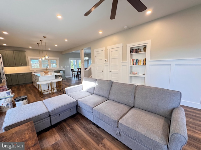 living room with ceiling fan with notable chandelier and dark wood-type flooring