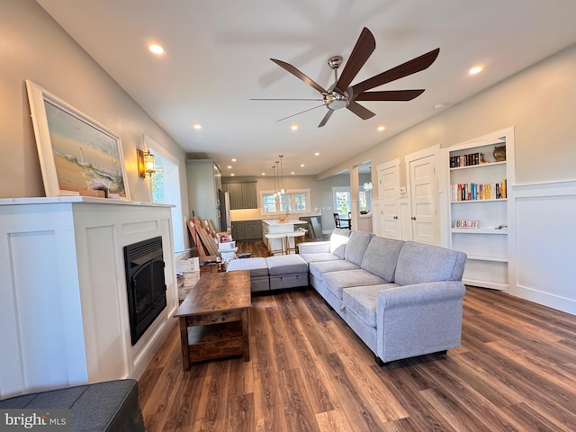 living room with dark hardwood / wood-style flooring, built in features, and ceiling fan