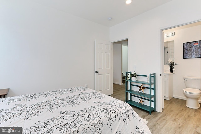 bedroom with connected bathroom and hardwood / wood-style flooring