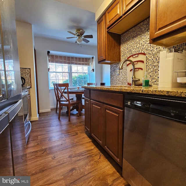 kitchen with light stone counters, dark hardwood / wood-style flooring, decorative backsplash, stainless steel dishwasher, and ceiling fan