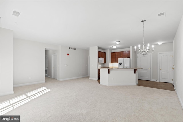 kitchen featuring light carpet, an inviting chandelier, hanging light fixtures, white appliances, and a kitchen island