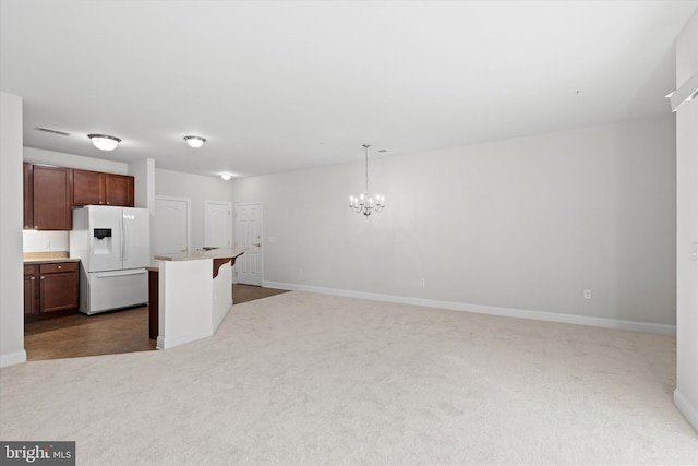 kitchen with a notable chandelier, decorative light fixtures, white refrigerator with ice dispenser, dark carpet, and a center island