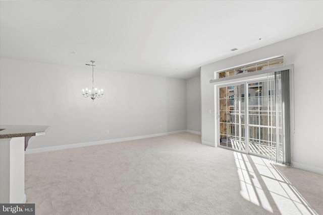 unfurnished living room featuring light colored carpet and a chandelier