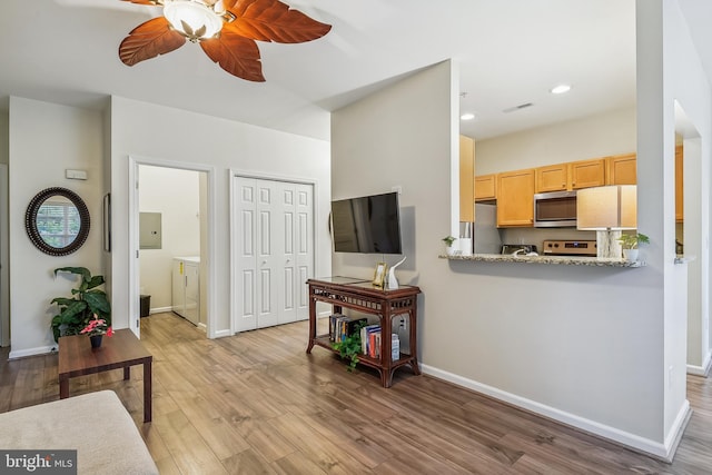 living room featuring ceiling fan, light wood-type flooring, and electric panel