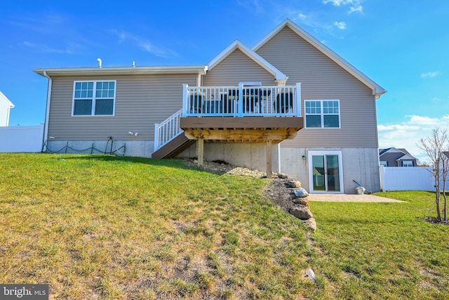 back of property with a lawn, a patio area, and a deck