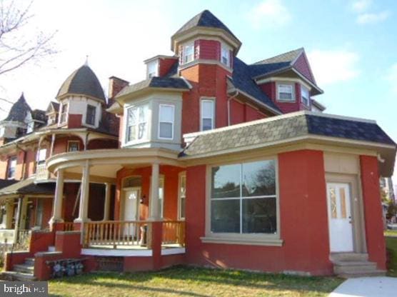 victorian-style house featuring covered porch and a front yard