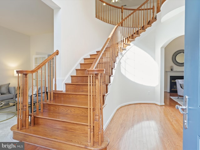 staircase with wood-type flooring and a high ceiling