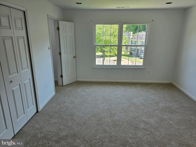 unfurnished bedroom with light colored carpet and a closet