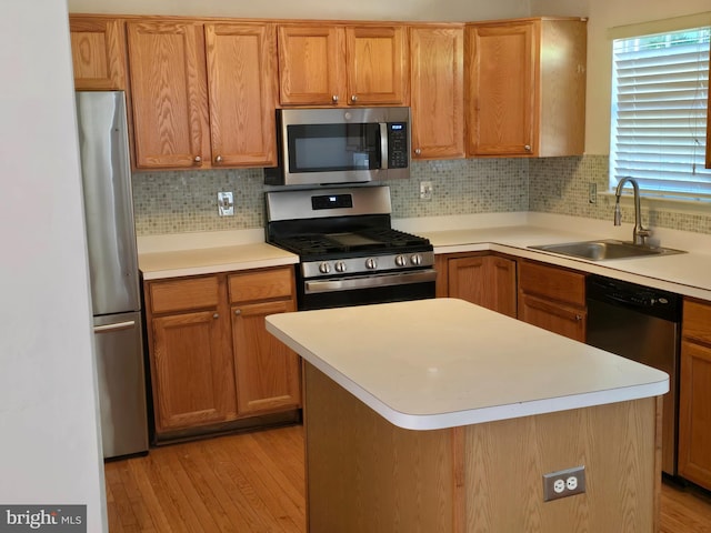 kitchen with light hardwood / wood-style floors, sink, a kitchen island, and appliances with stainless steel finishes