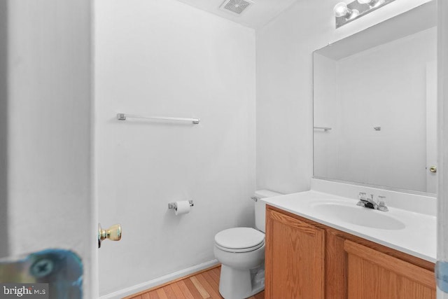 bathroom with wood-type flooring, toilet, and vanity