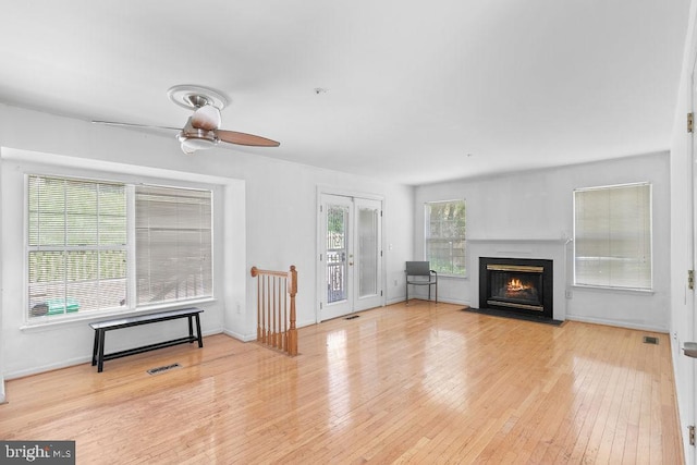 living room featuring light wood-type flooring, ceiling fan, and plenty of natural light