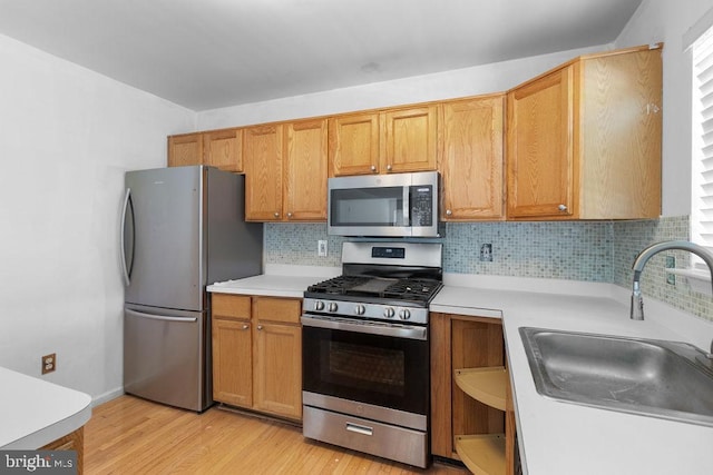 kitchen with stainless steel appliances, a wealth of natural light, sink, and light wood-type flooring