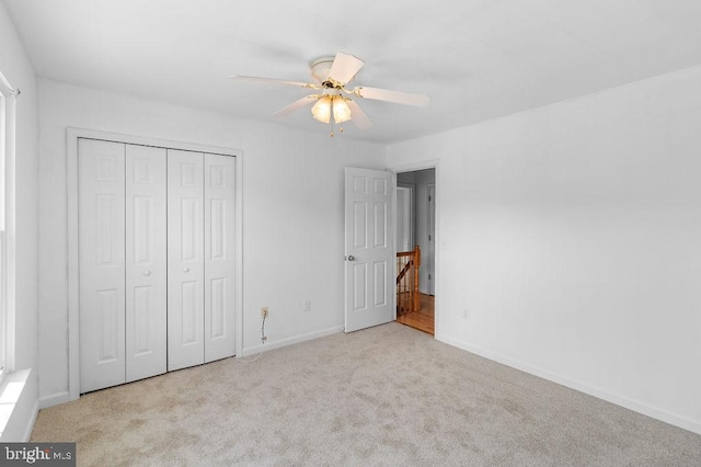 unfurnished bedroom featuring a closet, light colored carpet, and ceiling fan