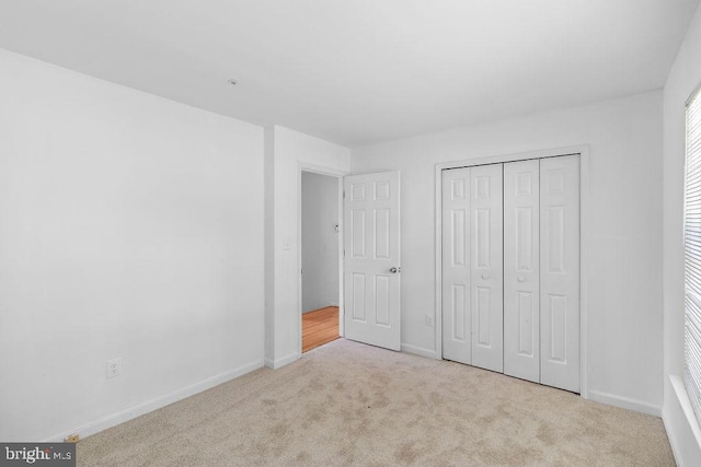 unfurnished bedroom featuring a closet and light colored carpet