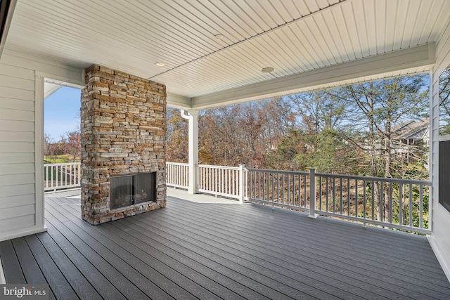 wooden deck featuring an outdoor stone fireplace