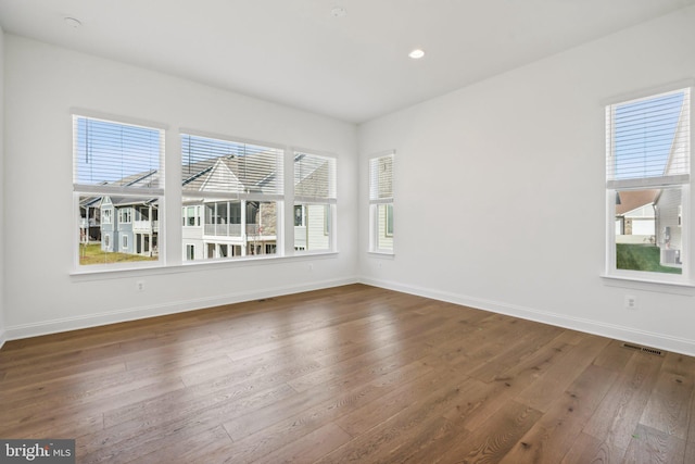 unfurnished room featuring a healthy amount of sunlight and dark hardwood / wood-style flooring