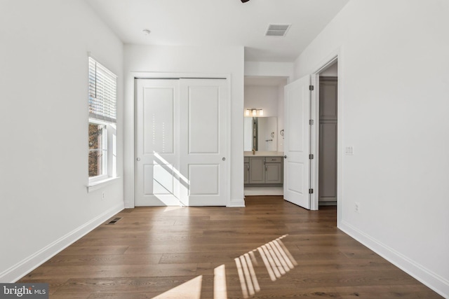 unfurnished bedroom with a closet, dark hardwood / wood-style floors, and ensuite bath