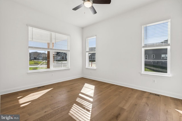 spare room featuring a wealth of natural light, ceiling fan, and dark hardwood / wood-style flooring