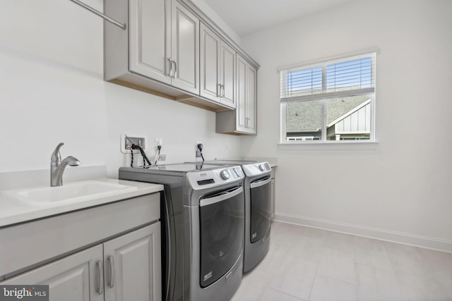 clothes washing area featuring washing machine and clothes dryer, cabinets, and sink