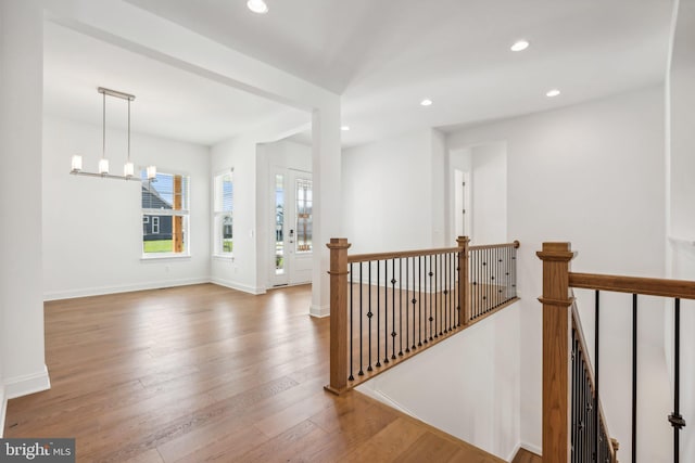 hall with wood-type flooring and a notable chandelier