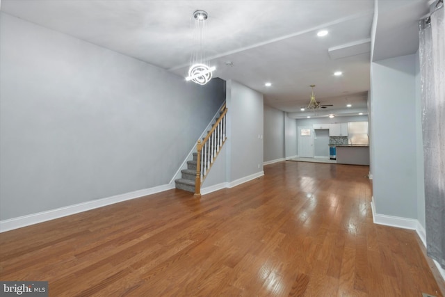 unfurnished living room featuring a notable chandelier and hardwood / wood-style flooring