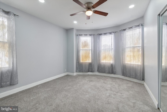 empty room with a wealth of natural light, ceiling fan, and carpet floors