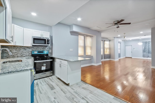 kitchen with light stone counters, light wood-type flooring, appliances with stainless steel finishes, sink, and white cabinets