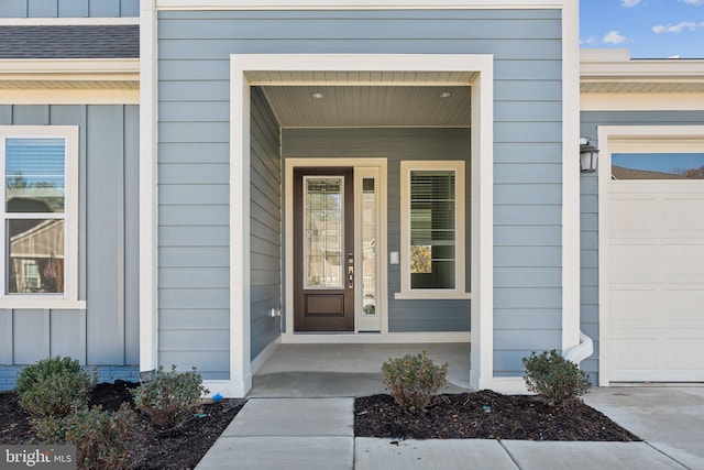 view of exterior entry with a garage and covered porch