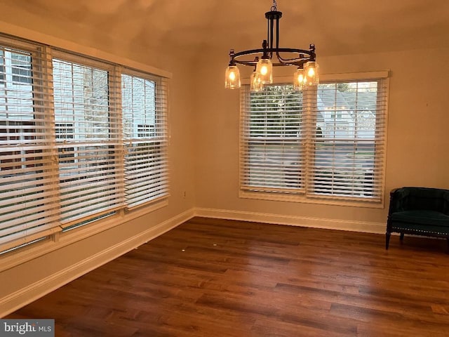 unfurnished dining area featuring dark hardwood / wood-style flooring and an inviting chandelier