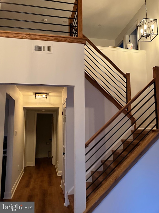 stairs featuring a chandelier and wood-type flooring