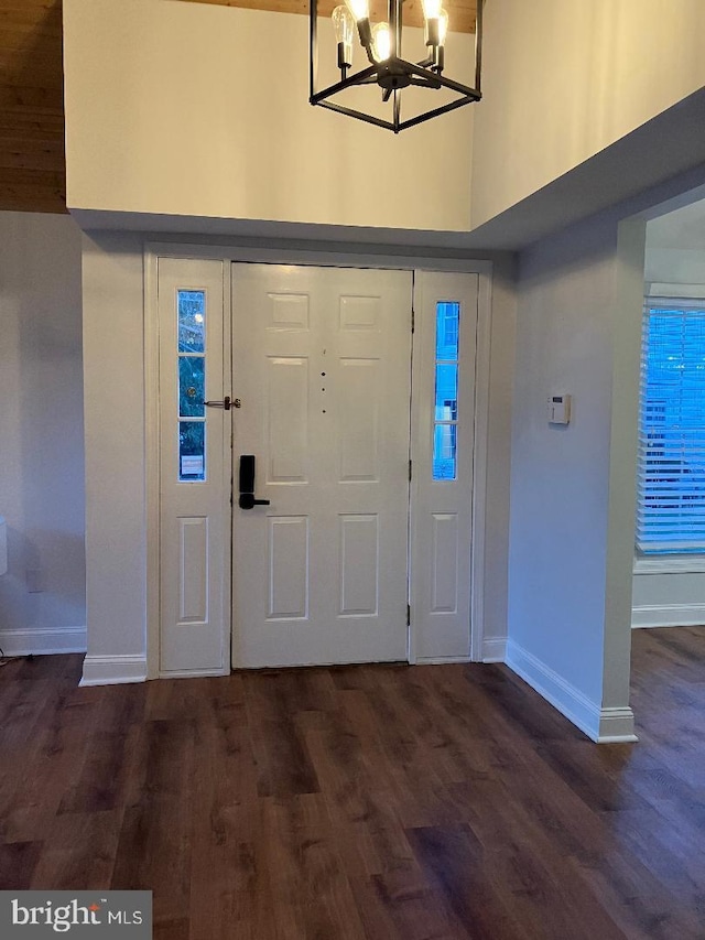 entryway with a towering ceiling, dark hardwood / wood-style flooring, and an inviting chandelier