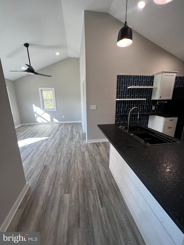 kitchen featuring white cabinetry, sink, decorative light fixtures, hardwood / wood-style floors, and vaulted ceiling